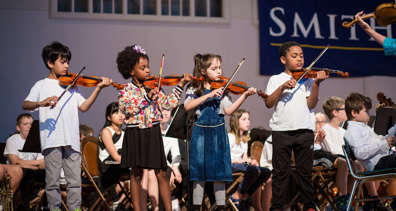 Students on stage playing violin