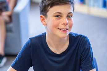 A boy in a blue shirt smiling.
