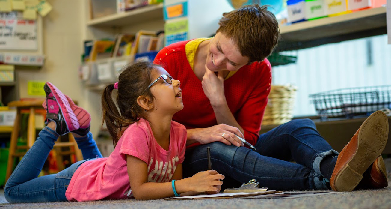 Teacher and student reading together on a rug