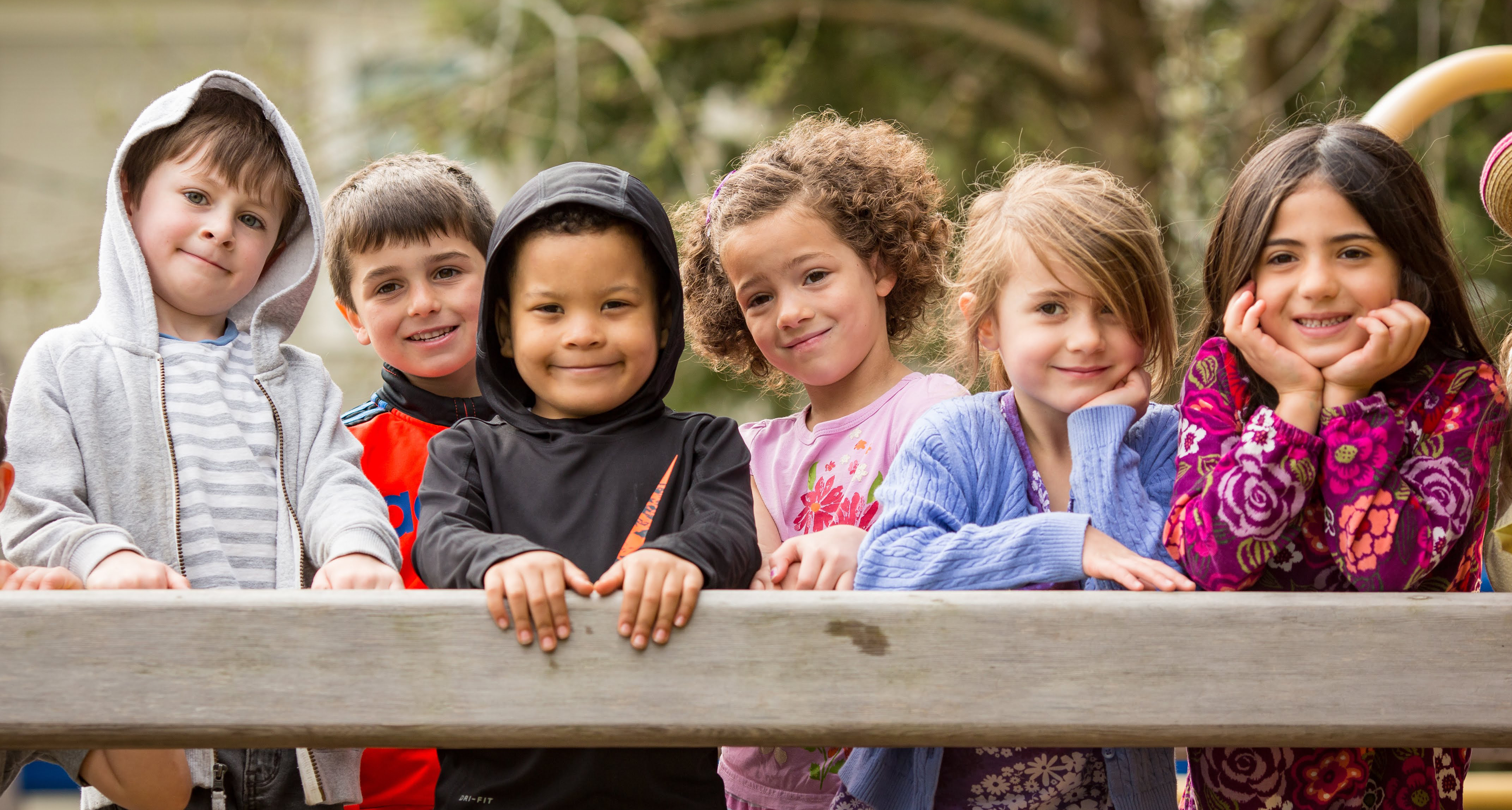 students smiling on a playground bridge