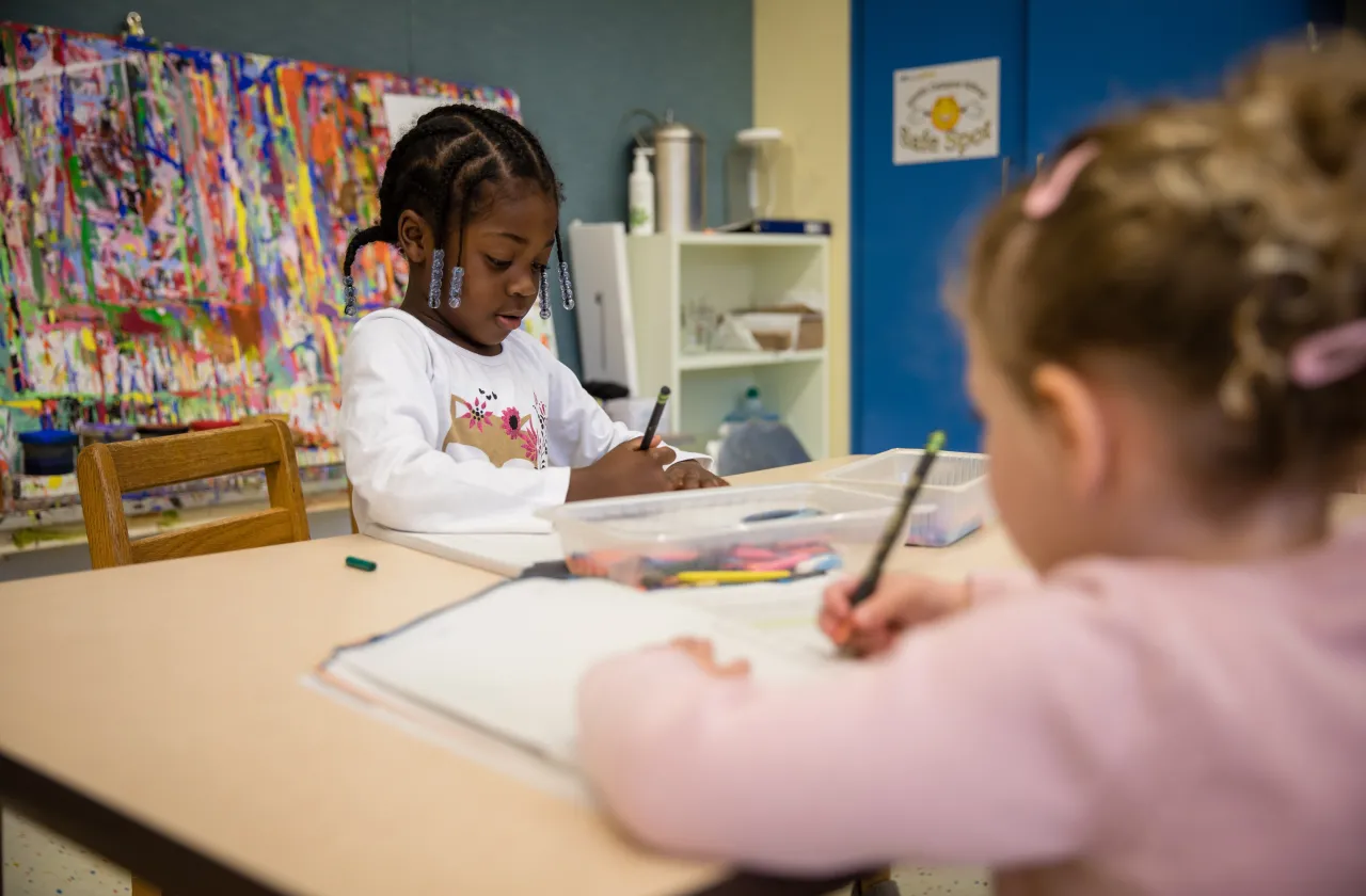 Two young schoolchildren at a desk writing.